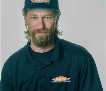 Man in a hat in a SERVPRO uniform posing for a picture on a white background