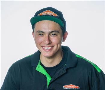 Man in a hat and SERVPRO uniform posing for a picture on a white background