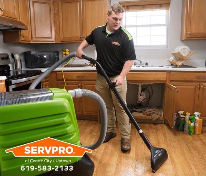 A SERVPRO technician is extracting water from a kitchen floor.