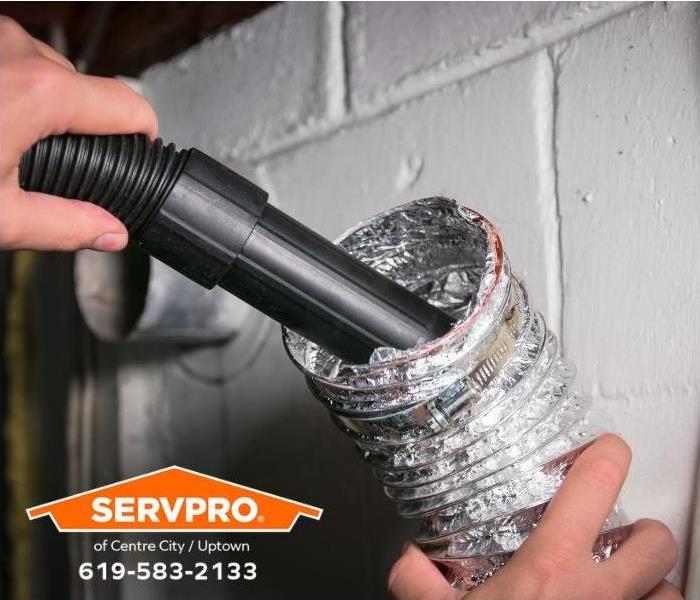 A person vacuums lint out of a dryer vent.