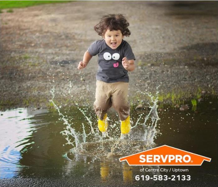 A child jumps in a puddle of water after a rainstorm.