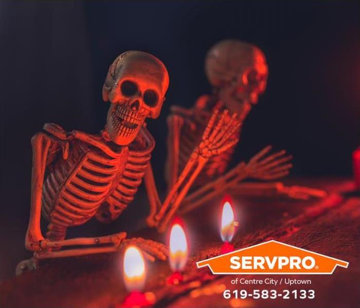 Candles sit close to a Halloween display of skeletons waving.